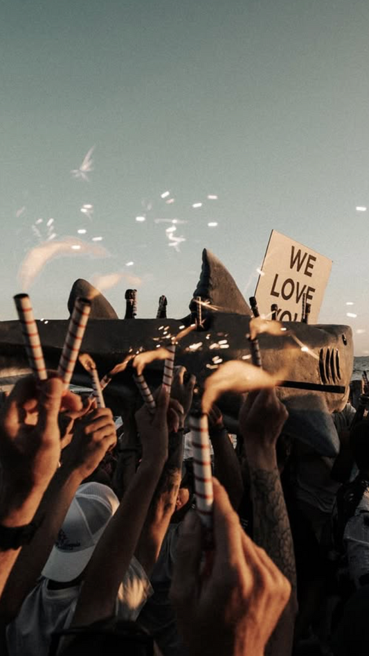 People with a shark-shaped object and fireworks at the beach