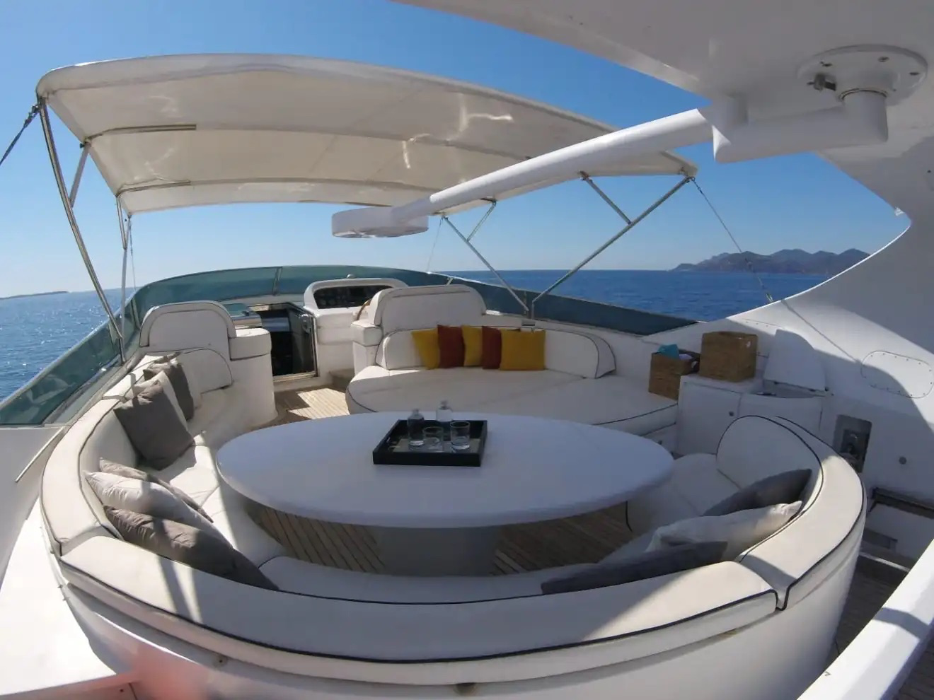 Yacht deck with seating area and table under a clear blue sky