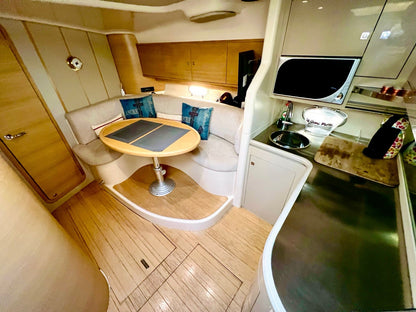 Interior of a boat cabin with a small table, seating area, and kitchenette.